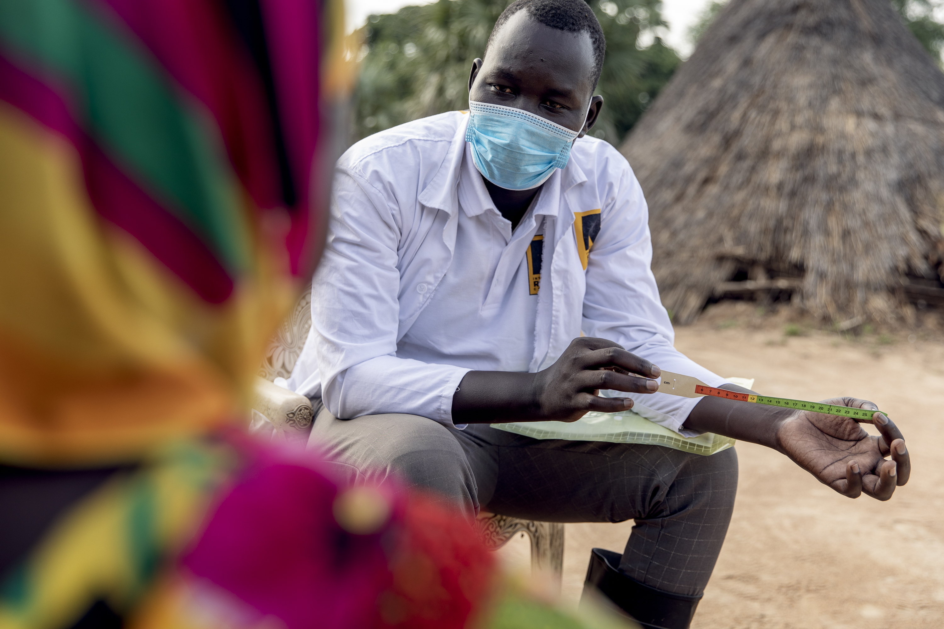 James from IRC takes care of Peter, held by his mother Abang, at home in Northern Bahr El Ghazal, South Sudan