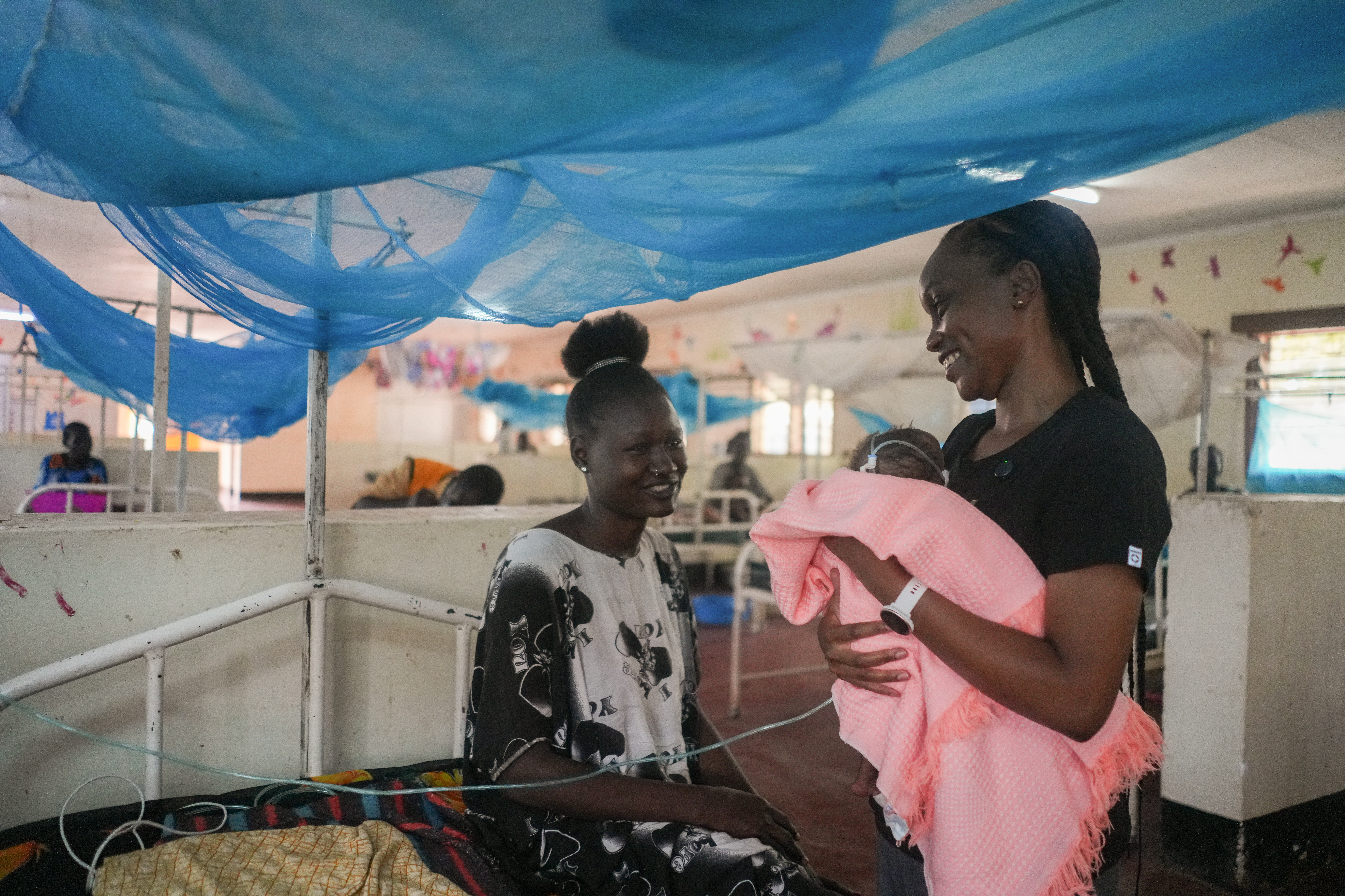 A caregiver smiles as she sees her child receive care at an IRC facility in Kakuma, Kenya