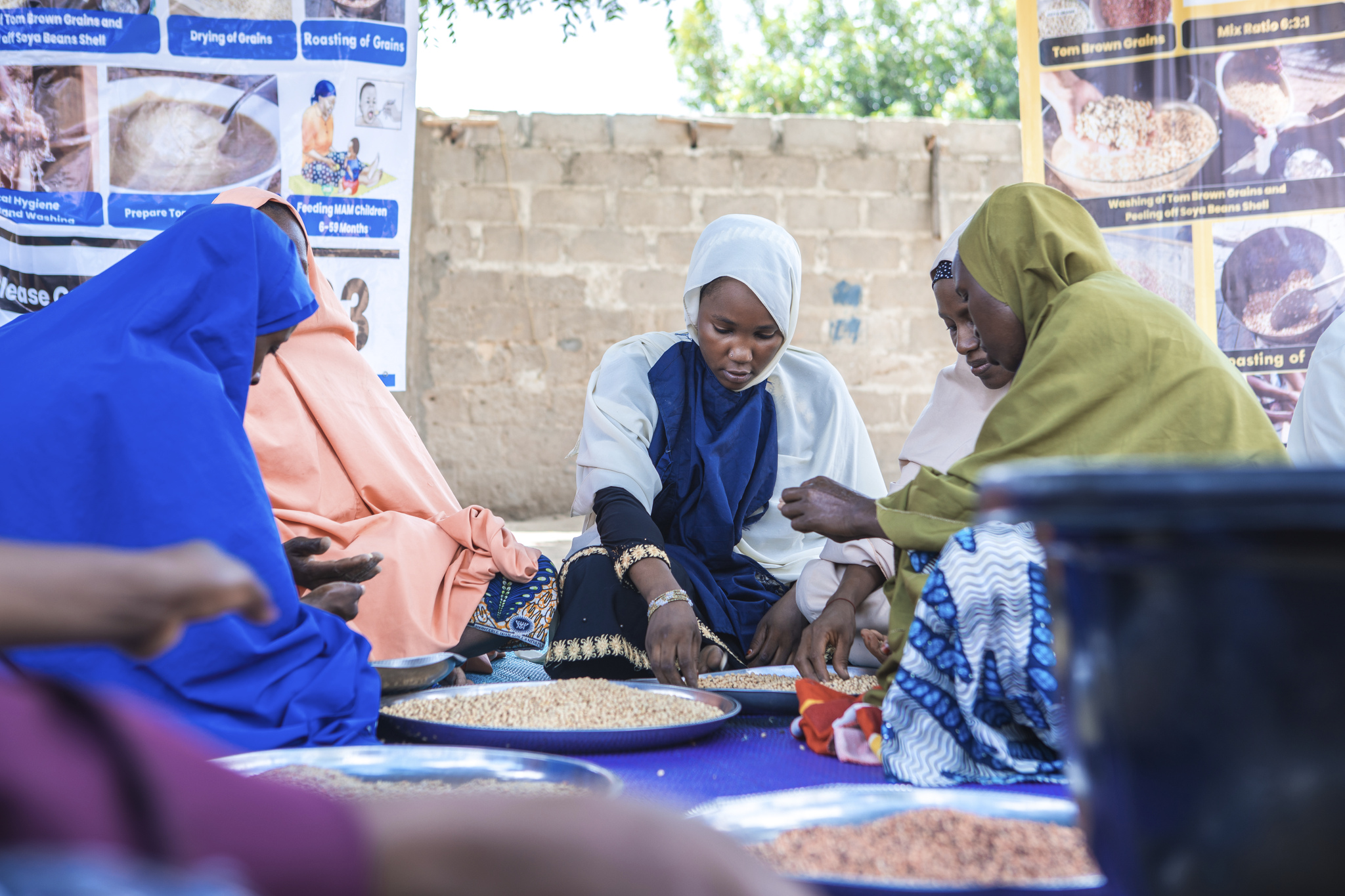 Caregivers in Maiduguri, Nigeria working with nutritious ingredients to be prepared using the Tom Brown method