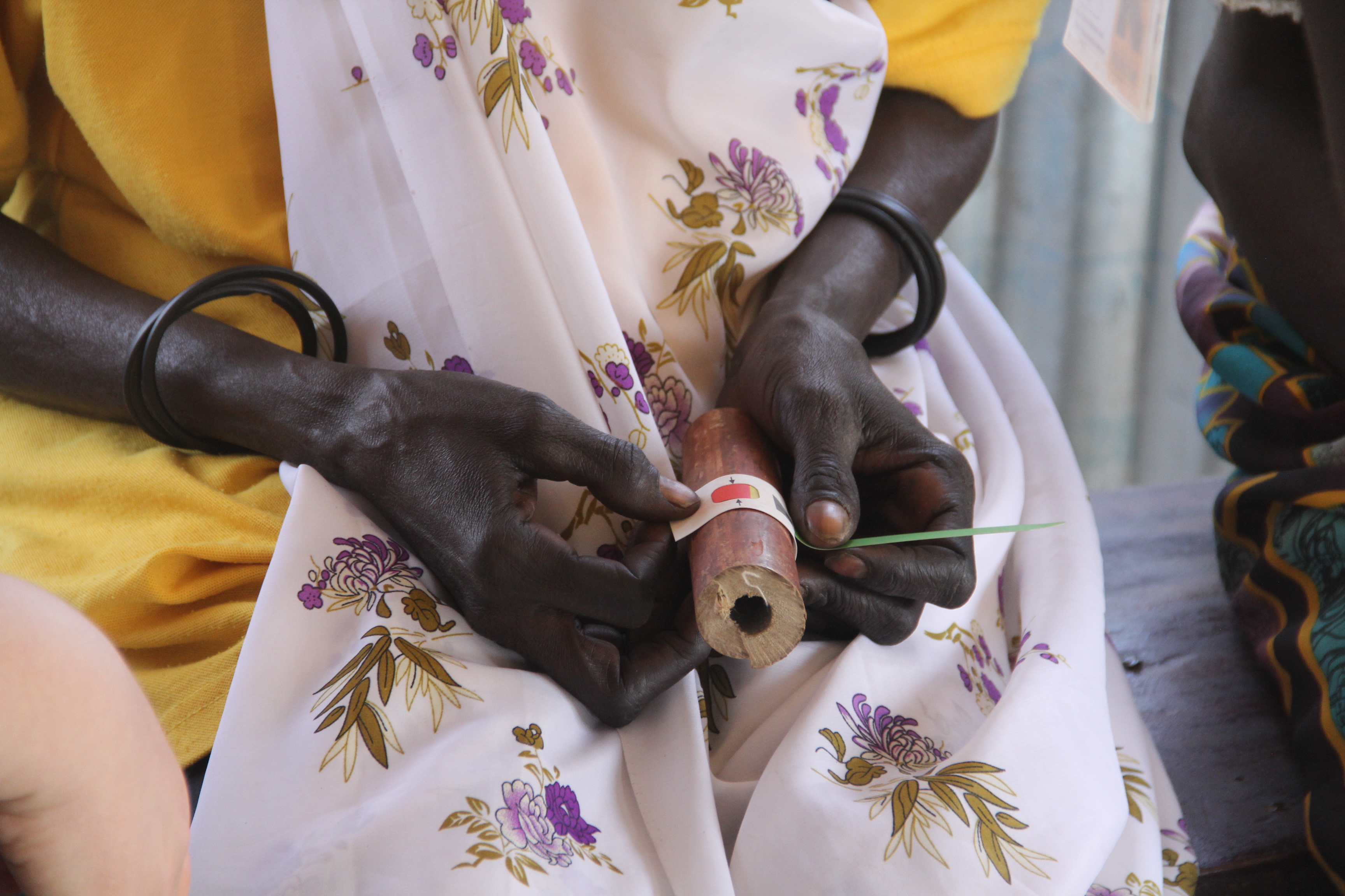A community health worker in South Sudan practices taking a MUAC measurement