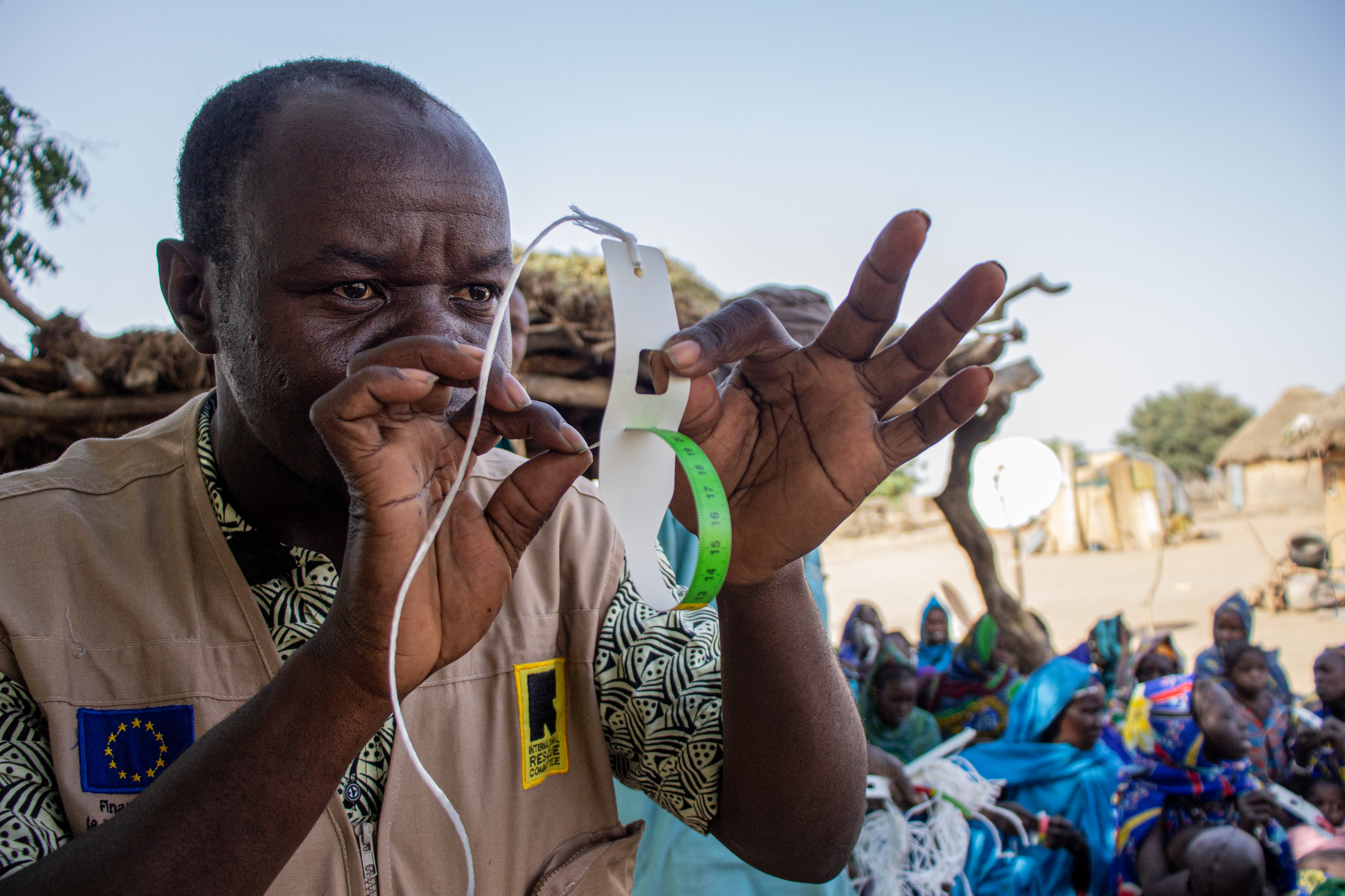 An IRC healthcare worker in Mali trains caregivers on correct MUAC measurement technique.
