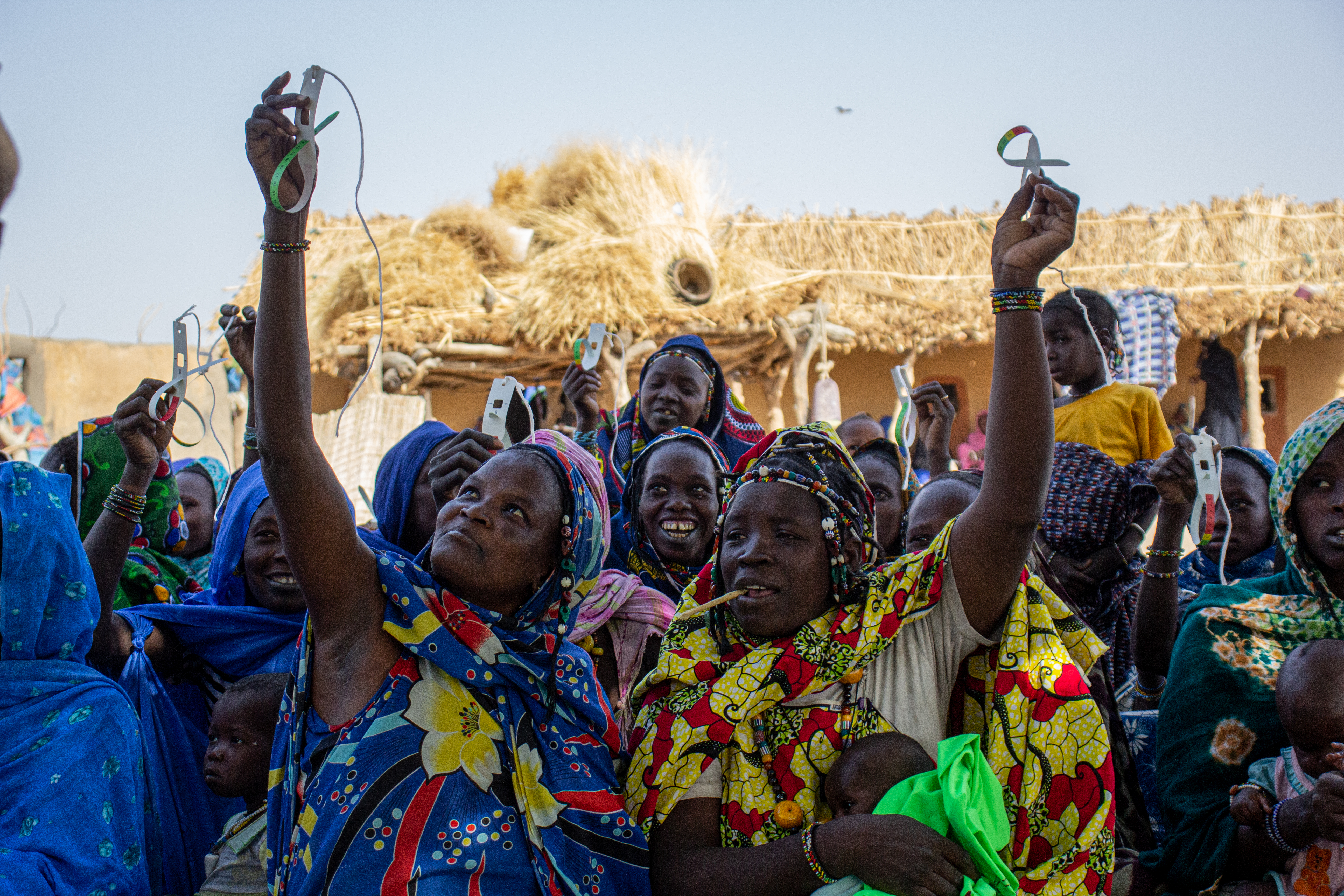 Caregivers in Nara, Mali proudly display their properly looped MUAC tapes at a community training