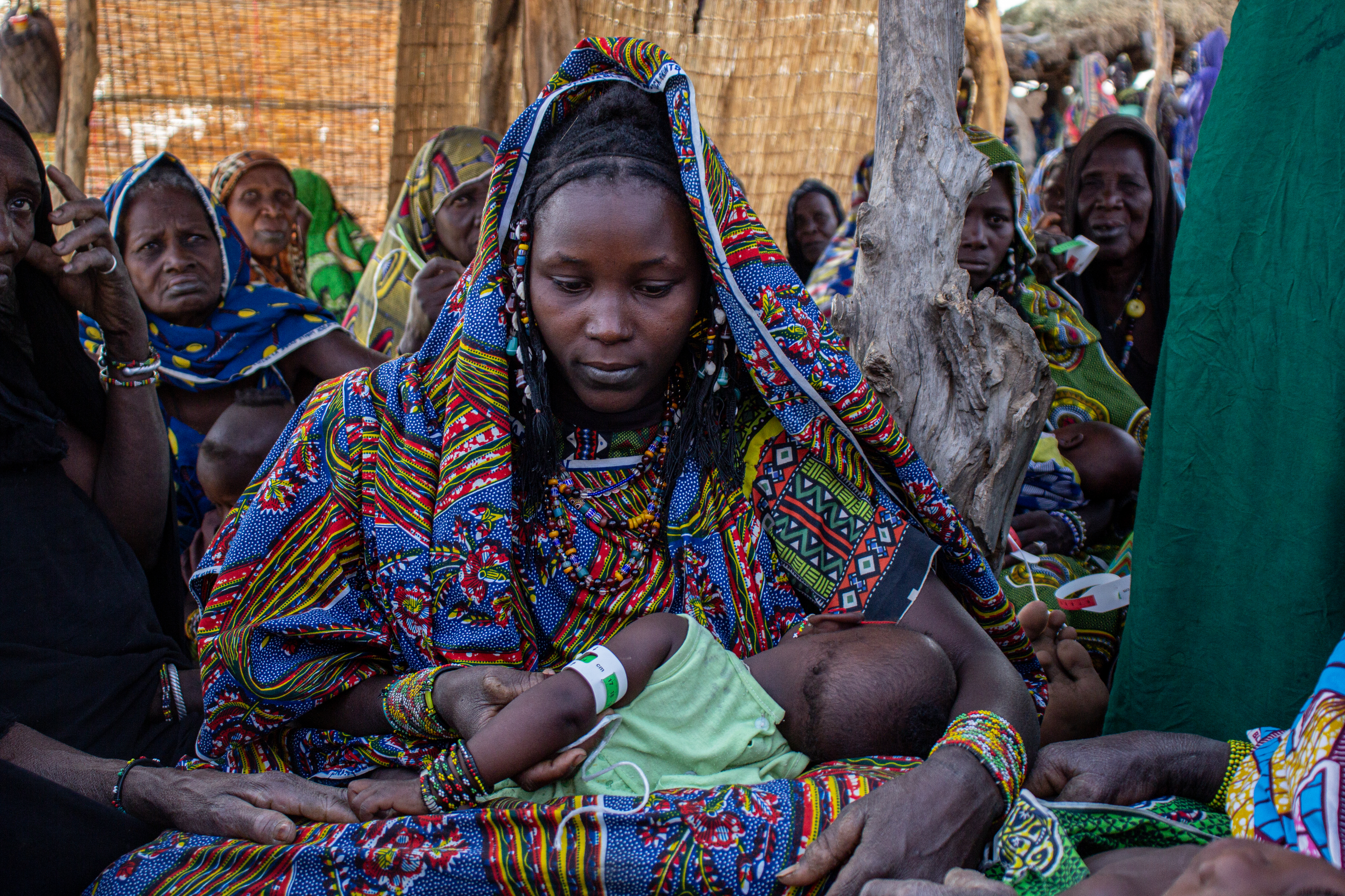 A caregiver in Mali practices taking a MUAC measurement of her child