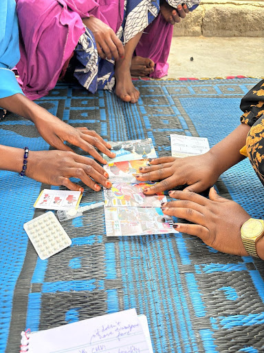 A client in Fariya IDP camp responding to the prototypes to indicate where she would like to get self-managed contraceptives from and why. Maiduguri, Nigeria, May 2024.